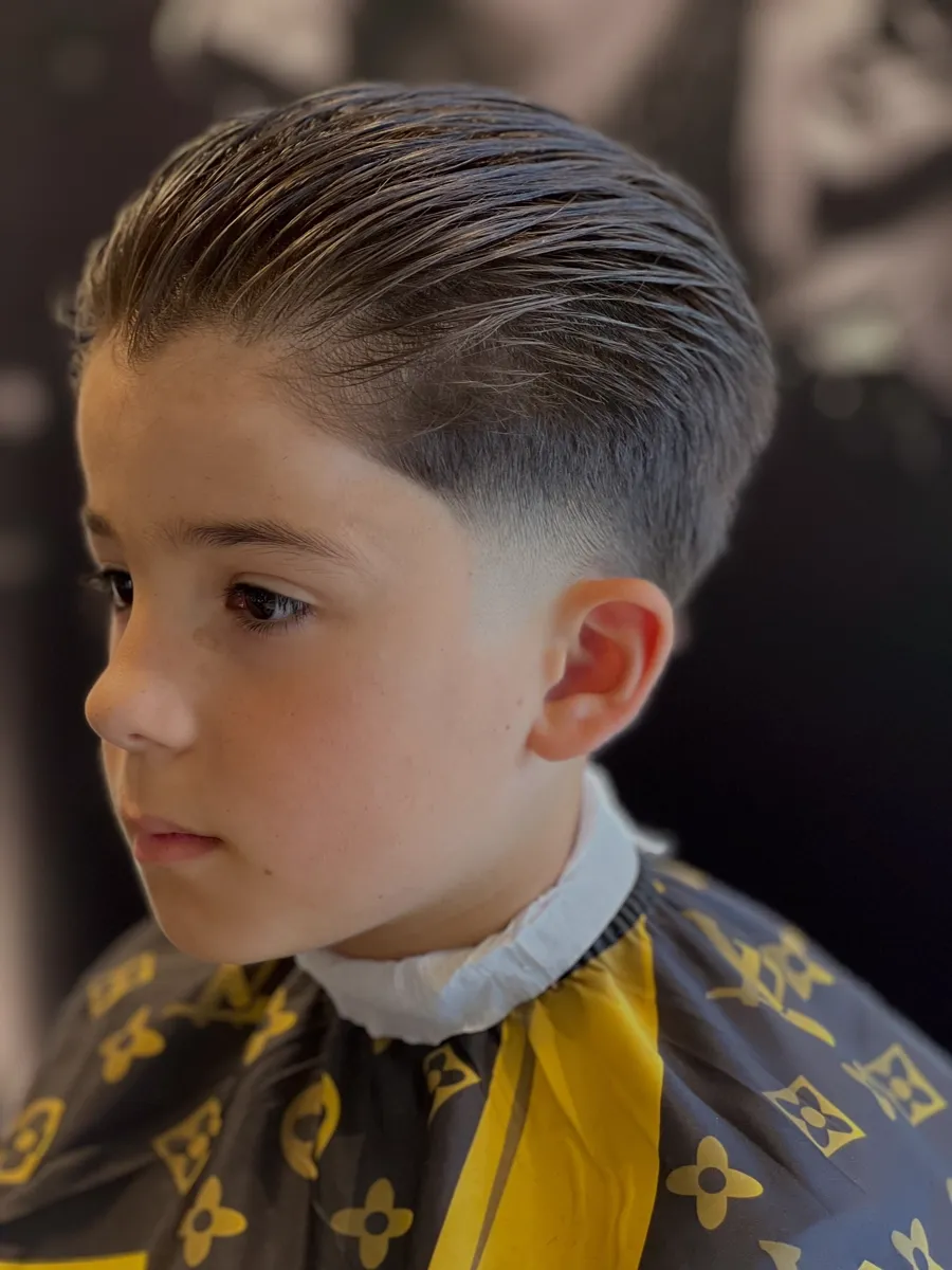 Child having a slicked back cut in the chair
